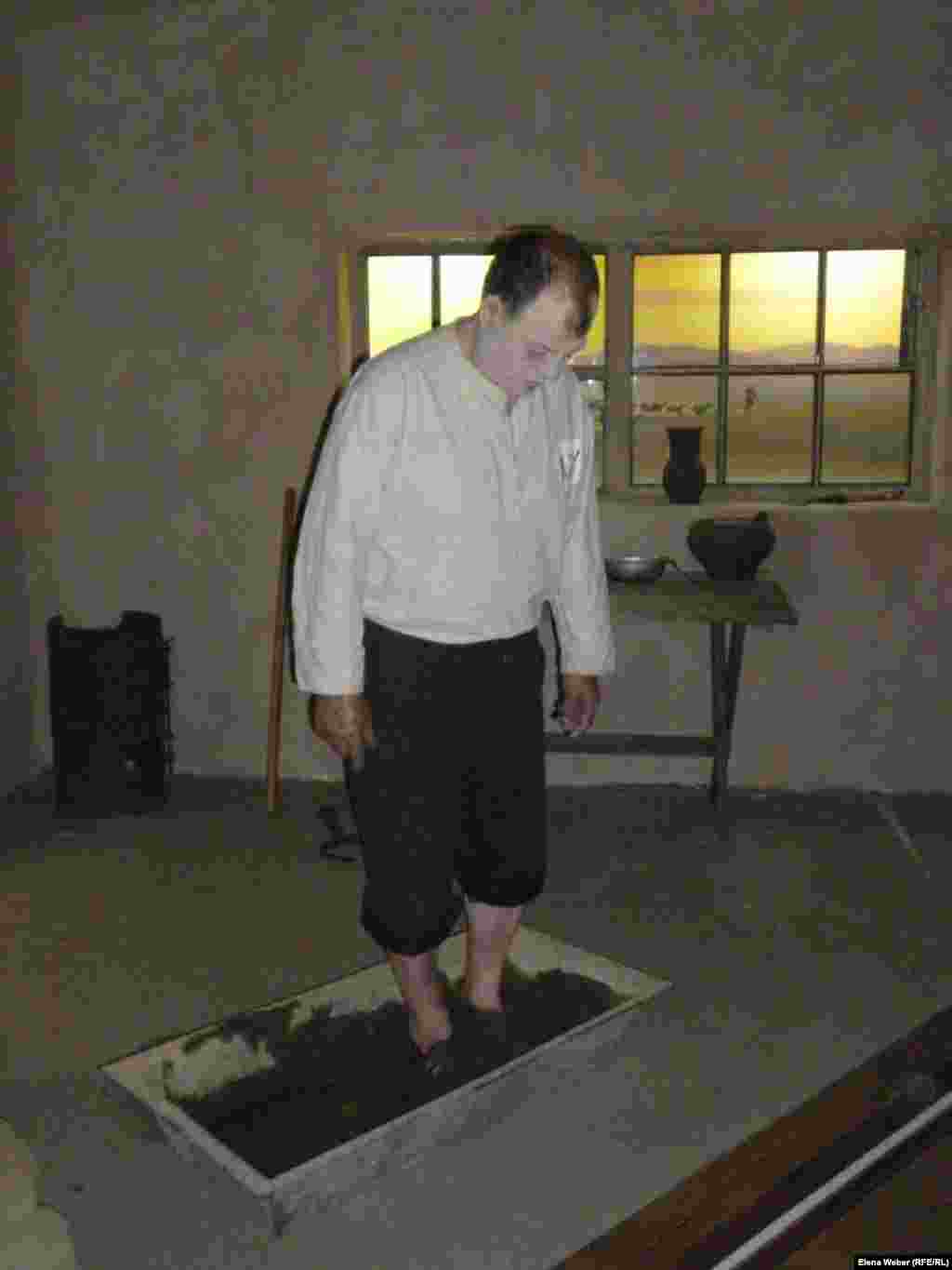 A museum employee demonstrates how hungry and exhausted prisoners used to churn clay with their feet to make mud bricks.