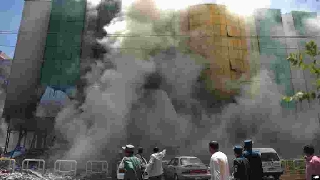 Afghan police and bystanders look on following a gas explosion at a shopping complex in Kabul. (AFP/Adek Berry)