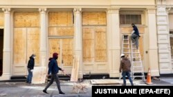 În SoHo, New York, muncitorii acoperă vitrinele cu placaj.