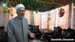 Samaritan elder Husni Cohen stands under a canopy of fresh fruit, a tradition that helps mark the community's Sukkot holiday.