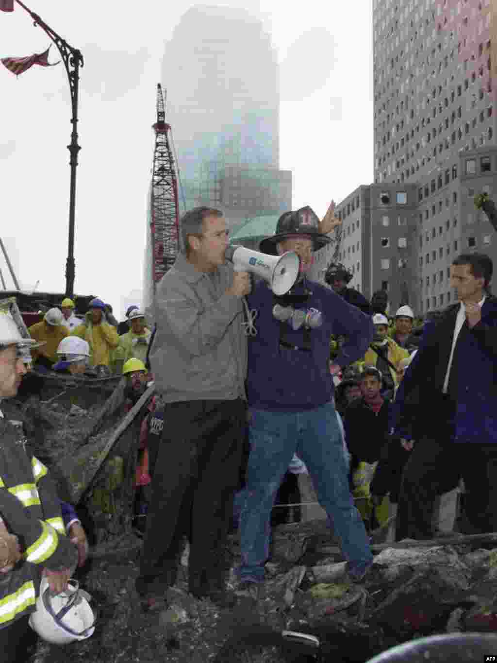 Presidenti Bush në rrënojat e Qendrës Botërore Tregtare, 14 shtator 2001. - bush20 UNITED STATES, New York : US President George W. Bush (L) speaks through a megaphone beside retired firefighter Bob Beckwith, 69, to firemen and other workers 14 September 2001 at the site of the destroyed World Trade Center. AFP PHOTO/Paul J. RICHARDS 