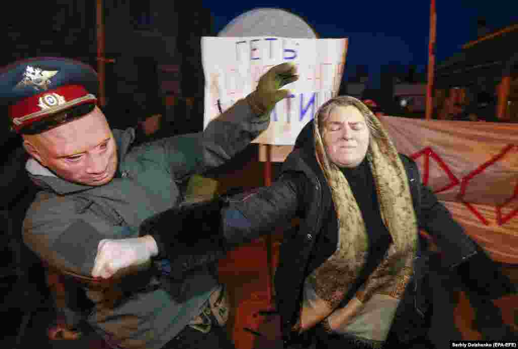 An Orthodox follower of the Moscow Patriarchate attacks a Ukrainian protester wearing a mask depicting Russian President Vladimir Putin in Kyiv. (epa-EFE/Sergey Dolzhenko)