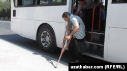 A disabled man is helped off a bus in Ashgabat by a fellow passsenger. (file photo)