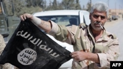 A Syrian government soldier displays an Islamic State (IS) group flag after Syrian troops regained control the previous day of Al-Qaryatain, a town in the province of Homs, earlier this month.