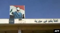 Purportedly a Syrian rebel defacing an image of President Assad at Bab al-Hawa border crossing between Syria and Turkey, on July 19