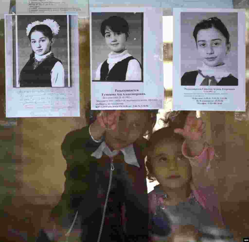 Two girls touch pictures of hostages who remained missing three days after the end of the hostage crisis.