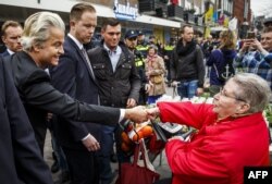 Dutch far-right parliamentary deputy Geert Wilders (left) shakes hands with a woman as he campaigns in Dordrecht for a no vote in the upcoming referendum on the EU's Association Agreement with Ukraine.