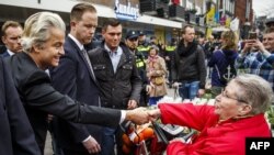 Dutch far-right parliamentary deputy Geert Wilders (left) shakes hands with a woman as he campaigns in Dordrecht for a no vote in the upcoming referendum on the EU's Association Agreement with Ukraine.