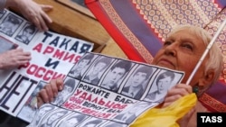 A woman holds a placard with victims of hazing during a protest against conscription in Moscow in 2006