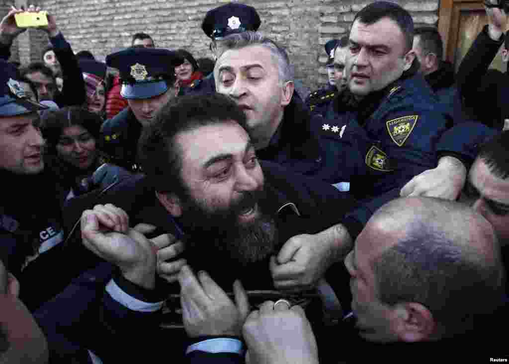 Police detain an Orthodox activist in front of the Georgian Patriarchate in Tbilisi, where clashes erupted over Patriarch Ilia II&#39;s suggestion in his Christmas address that children born to surrogate mothers or through artificial insemination will be &quot;problematic&quot; in adulthood. (Reuters/David Mdzinarishvili)