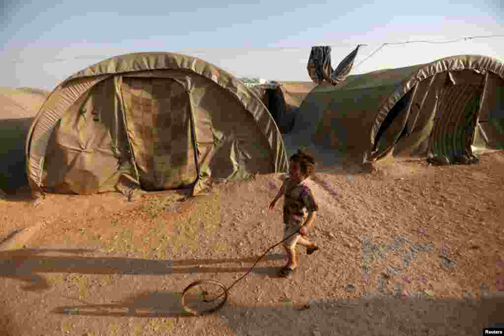 An internally displaced Syrian boy plays with a wheel in Jrzinaz camp, in the southern part of Idlib, Syria. (Reuters/Khalil Ashawi)