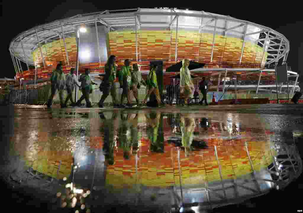 Staff walk outside the center court stadium during a rain delay in the tennis competition.