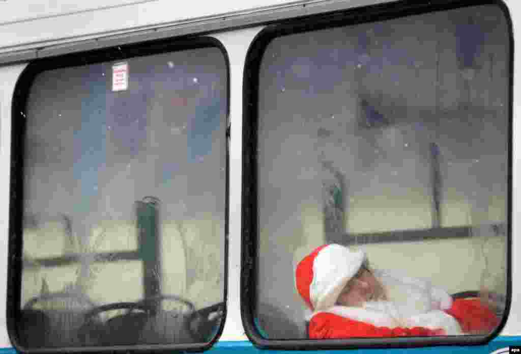 A man wearing a Ded Moroz (Grandfather Frost) costume sleeps in a bus before a Christmas parade in the center of Minsk, Belarus, on December 25. (epa/​Tatyana Zenkovich)