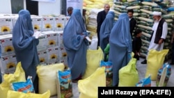 Afghan families receive aid rations from Turkish Aid group TIKA during a Ramadan food drive in Herat.