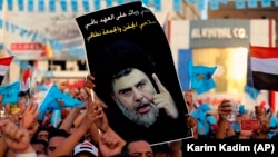 Followers of Shiite cleric Muqtada al-Sadr, seen in the poster, take part in a campaign rally ahead of May 12 parliamentary elections in Tahrir Square, Baghdad, Iraq, Friday, May 4, 2018.