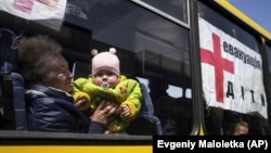 A woman with a child from Siversk look though the window of a bus during evacuation near Lyman, Donetsk region, in May.