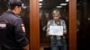 Aleksei Gorinov, accused of spreading "knowingly false information" about the Russian Army fighting in Ukraine, held up a sign reading, "Do you need this war?" during the verdict hearing in his trial at a courthouse in Moscow on July 8.
