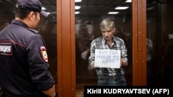 Aleksei Gorinov, accused of spreading "knowingly false information" about the Russian Army fighting in Ukraine, held up a sign reading, "Do you need this war?" during the verdict hearing in his trial at a courthouse in Moscow on July 8.