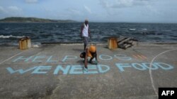 Filipine - Një njeri shkruan porosi në një fushë basketbolli "Ndihmë, SOS, kemi nevojë për ushqim" (Ilustrim)