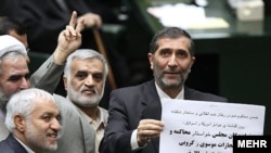 A member of parliament shows a sign calling for Musavi and Karrubi to be tried.