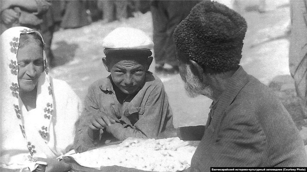 Уличный торговец в Бахчисарае, 1920-е годы. Большинство ремесленников сами продавали свои товары в магазинах, но в каждом крымском городке также были и шумные базары. Уличные торговцы продавали ожерелья, цепочки, платья и чубуки&nbsp;&ndash; часть курительной трубки.