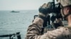 A U.S. Marine observes an Iranian fast attack craft from USS John P. Murtha during a Strait of Hormuz transit, Arabian Sea off Oman, in this picture released by U.S. Navy on July 18, 2019.