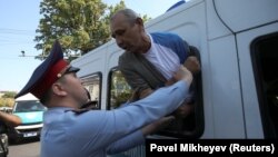 Задержанный в окне автозака и сотрудник полиции. Алматы, 21 сентября 2019 года.