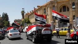 طرفداران بشار اسد با خواندن سرودهای ملی و به اهتزاز در آوردن پرچم‌های این کشور در خیابان‌های دمشق رژه می‌روند.