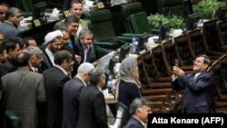Iranian foreign ministry official Hassan Ghashghavi (R) uses a cell phone to take a picture of EU foreign policy chief Federica Mogherini (C) standing with Iranian MPs, after he told them it is better to take a group photo.