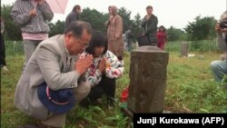 In a 1989 photo, Japanese visitors pray at a cemetery in Kunashir, part of the disputed island chain.