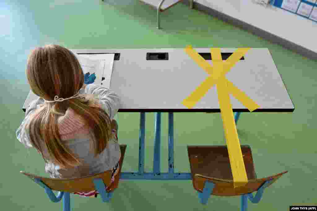A pupil of the Sainte-Croix elementary school works as half of her writing desk is marked with a tape to ensure that safe distance is kept on May 15, 2020 in Hannut, as the lockdown introduced two months ago to fight the spread of the Covid-19 disease caused by the novel coronavirus is progressively easing.