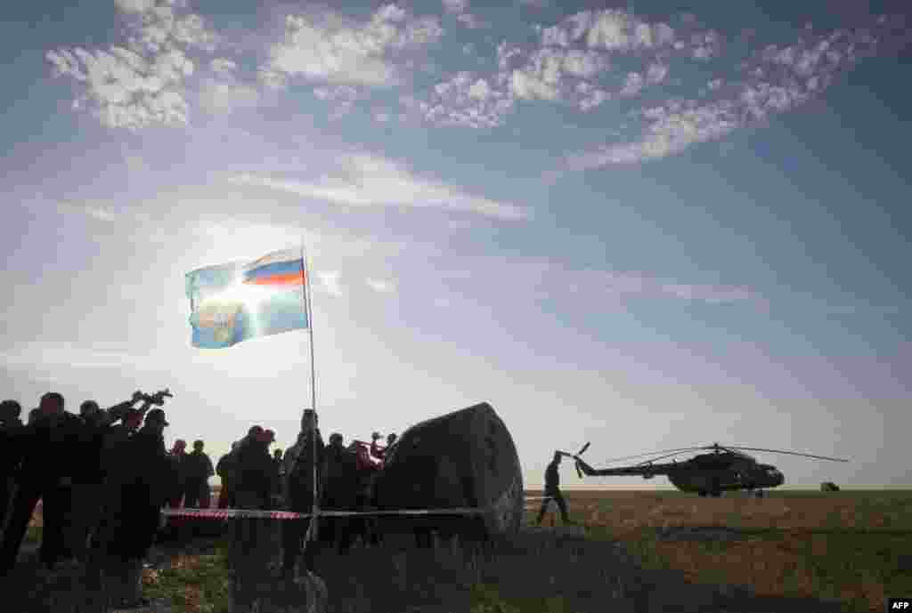 Search-and-rescue personnel surround the Soyuz capsule.