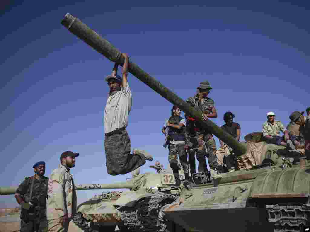 A transitional council fighter hangs from the gun turret of a tank in Wadi Dinar, Libya on September 21. (Photo taken by Alexandre Meneghini for AP)