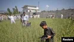 FILE: A boy collects debris as journalists surround the compound where al Qaeda leader Osama bin Laden was killed in Abbottabad (May 2011).