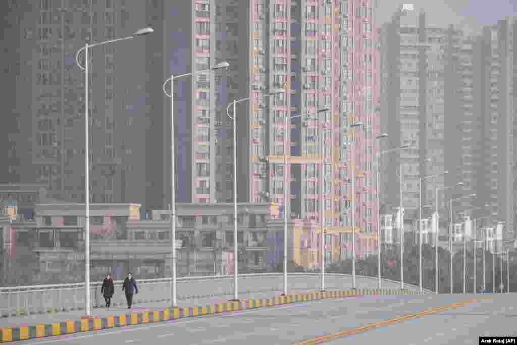People wearing face masks walk down a deserted street in the central Chinese city of Wuhan, which is at the center of the coronavirus outbreak. (AP/Arek Rataj)