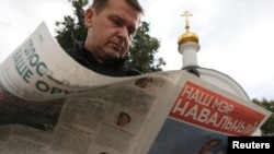 A man reads campaign literature of opposition leader Aleksei Navalny on a street in Moscow, September 3, 2013