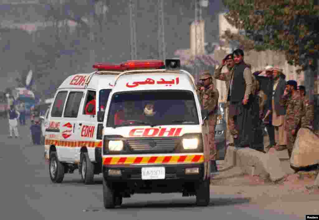 Ambulances drive away from a military-run school that came under attack by Taliban gunmen in Peshawar.