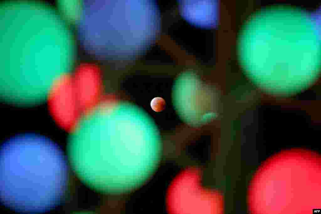 The moon is shown during a total lunar eclipse, also known as a &quot;blood moon,&quot; in a photograph taken on July 27 as it passed through decorative lights in Kuwait City. (AFP/Yasser Al-Zayyat)