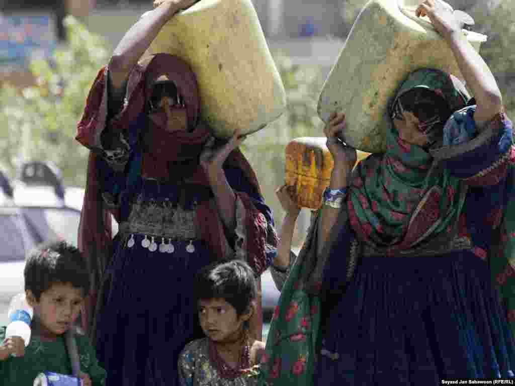 Afghan women carry cans of drinking water in Kabul on January 17. Many years of conflict and several seasons of severe drought have damaged the water-supply network and dried out dams and walls in Kabul and in many other parts of Afghanistan, leaving large sections of the population without access to clean water. Photo by Sayaed Jan Sabawoon for RFE/RL