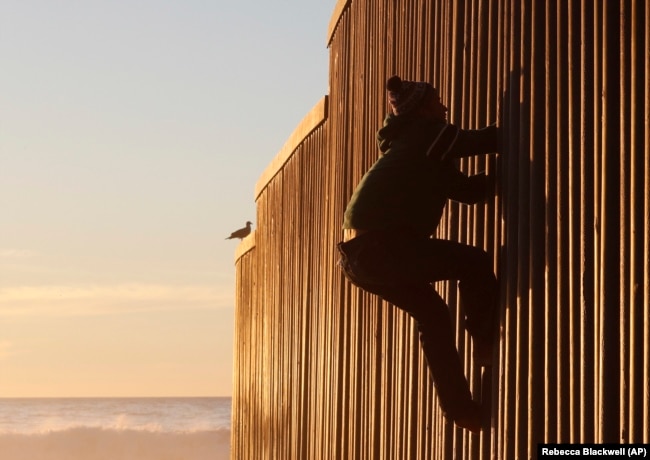 Një migrant nga Hondurasi duke tentuar të kalojë në anën amerikane të kufirit mes Meksikës dhe Shteteve të Bashkuara.