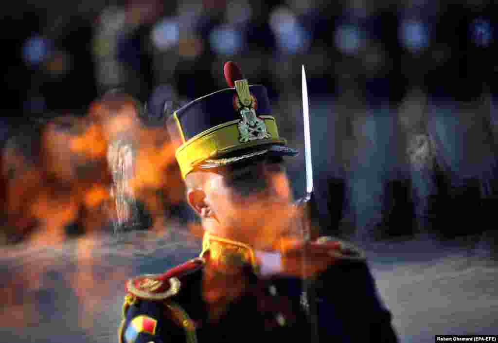 A Romanian honor guard soldier stands at attention as seen through the eternal flame at the Unknown Soldier Memorial during the Romanian Army Day celebration in Bucharest. (EPA-EFE/Robert Ghement)