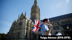 Маж го вее британското знаме пред катедрала во Солсбери 