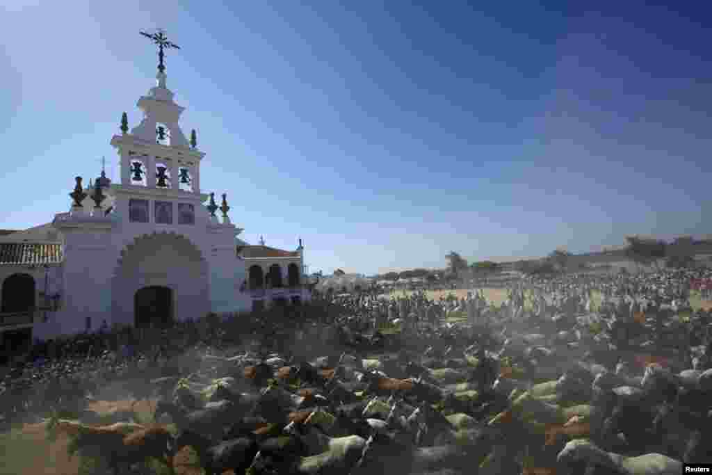 Wild mares trot past the shrine of El Rocio as drovers take them to a livestock fair in Almonte, southern Spain. (Reuters/Marcelo del Pozo)