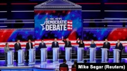 Senator Bernie Sanders və Senator Kamala Harris debat zamanı əllərini qaldırır
