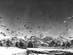UN troops and equipment float to Earth during a massive airdrop in 1951.