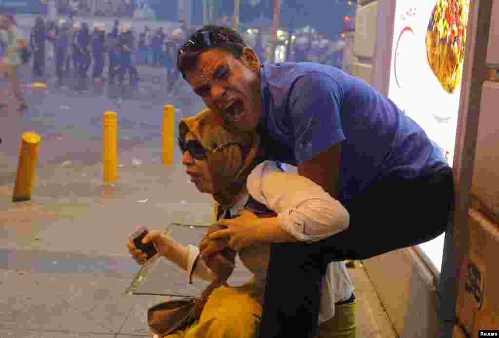 A couple is overcome by tear gas used by riot police to disperse demonstrators in central Istanbul. Police in Istanbul fired tear gas and water cannon when a demonstration by protesters blaming the government for a suspected Islamic State suicide bombing turned violent. (Reuters/Huseyin Aldemir)