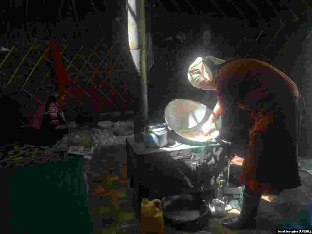 A woman cooking. Women work from early morning till late at night. In addition to cooking and childcare, they milk the yaks twice a day and dig tersken, a shrub used for heating and cooking.