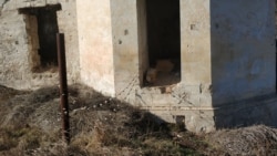 Проволока ограды прикреплена к вбитому в древнюю стену гвоздю