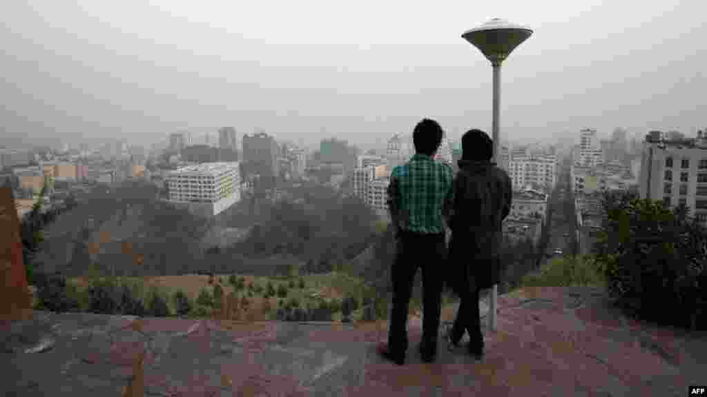 A couple stands at a viewpoint in the north of Tehran overlooking the capital, which is covered by smog. Schools, universities, and government agencies in Tehran will be closed on December 4-5 due to pollution. (AFP)