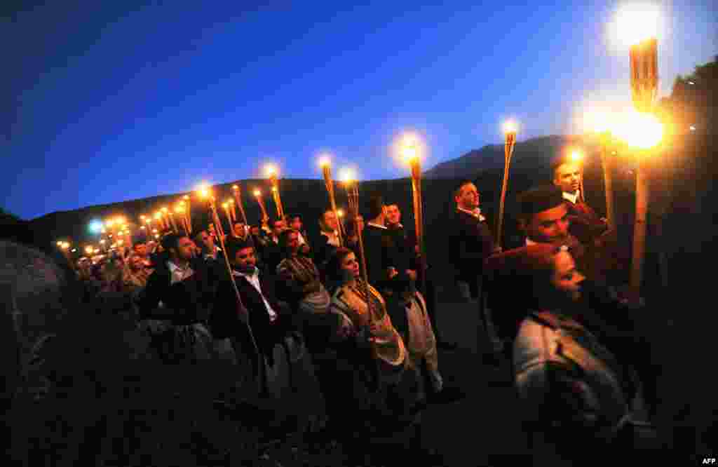 Men and women with torches participate in the wedding procession the night before a typical marriage in the western Macedonian village of Galicnik, some 150 km southwest of the capital, Skopje, on July 16. Every year, around the time of the Christian Orthodox St. Peter's Day holiday, Macedonians originating from Galicnik gather in this almost deserted mountainous village and a couple gets married according to the old traditions of this region.Photo by Robert Atanasovski for AFP